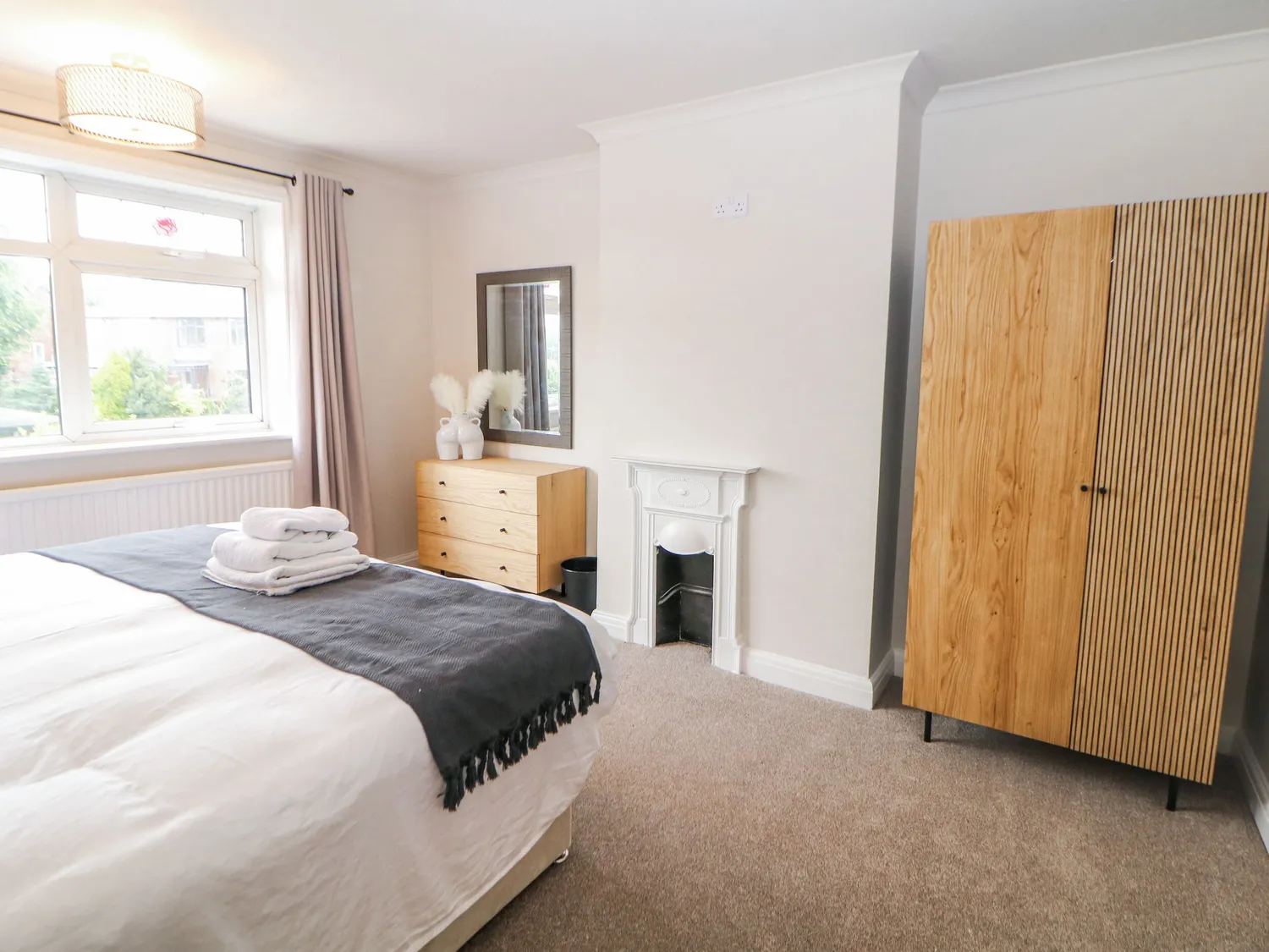 Double bedroom with slatted wood wardrobe and period fireplace