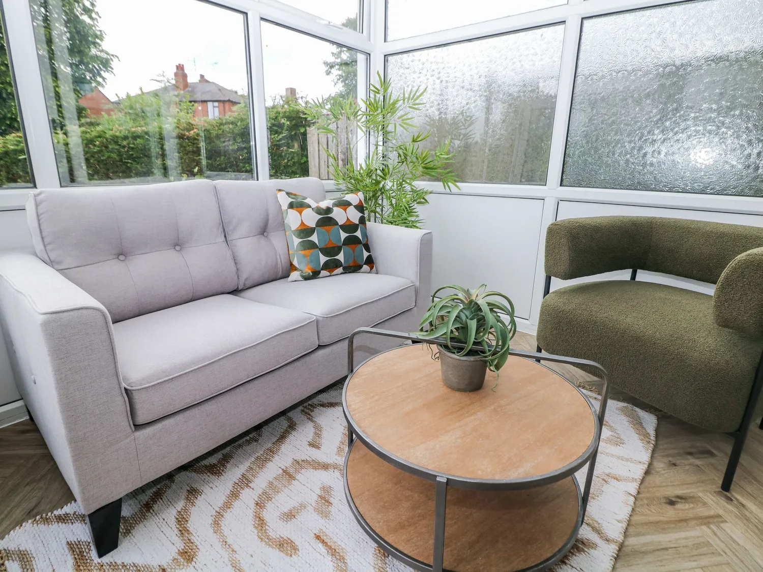 Bright conservatory with grey sofa and green boucle armchair