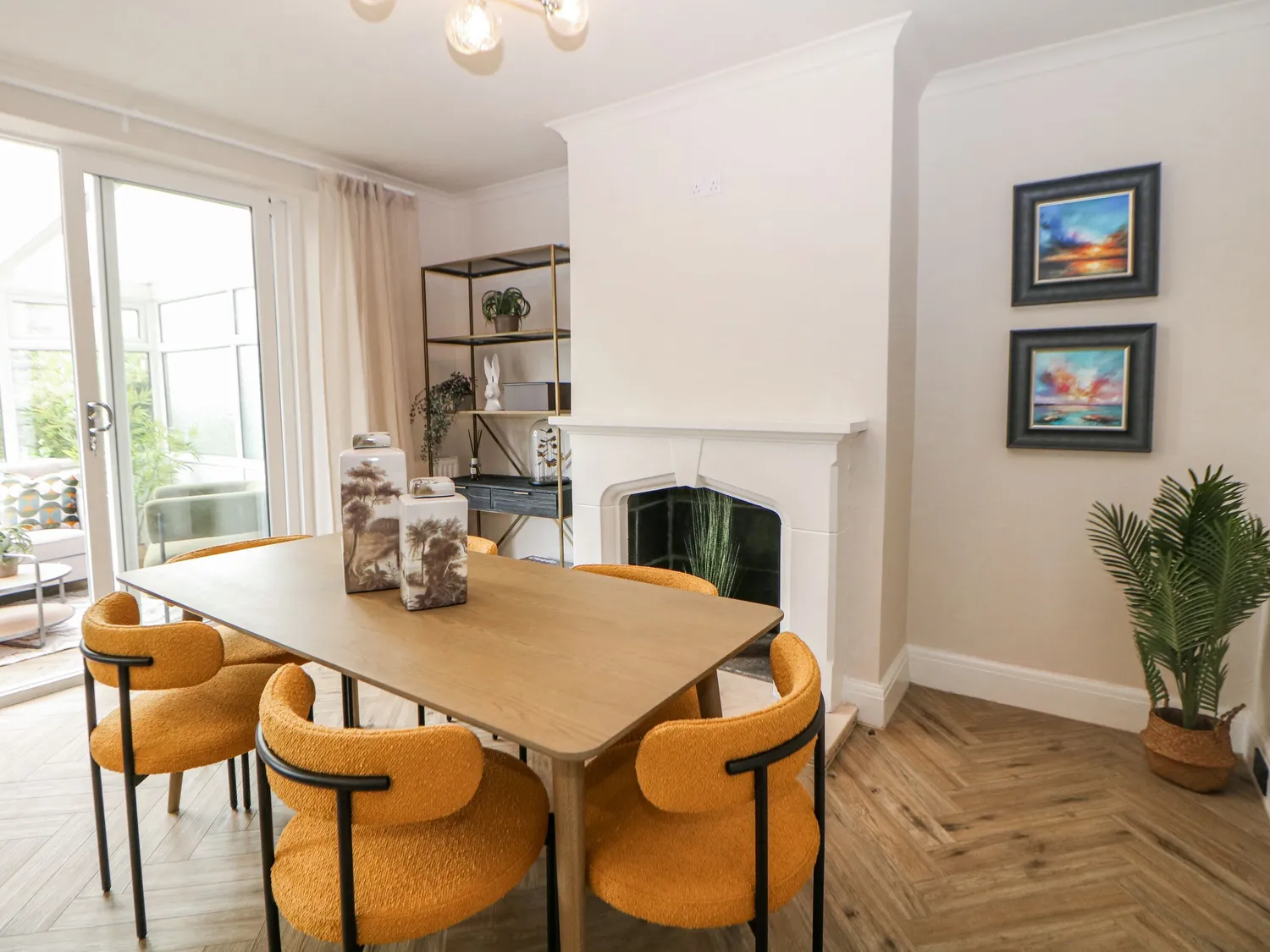 Dining room with oak table, mustard boucle chairs and coastal sunset prints