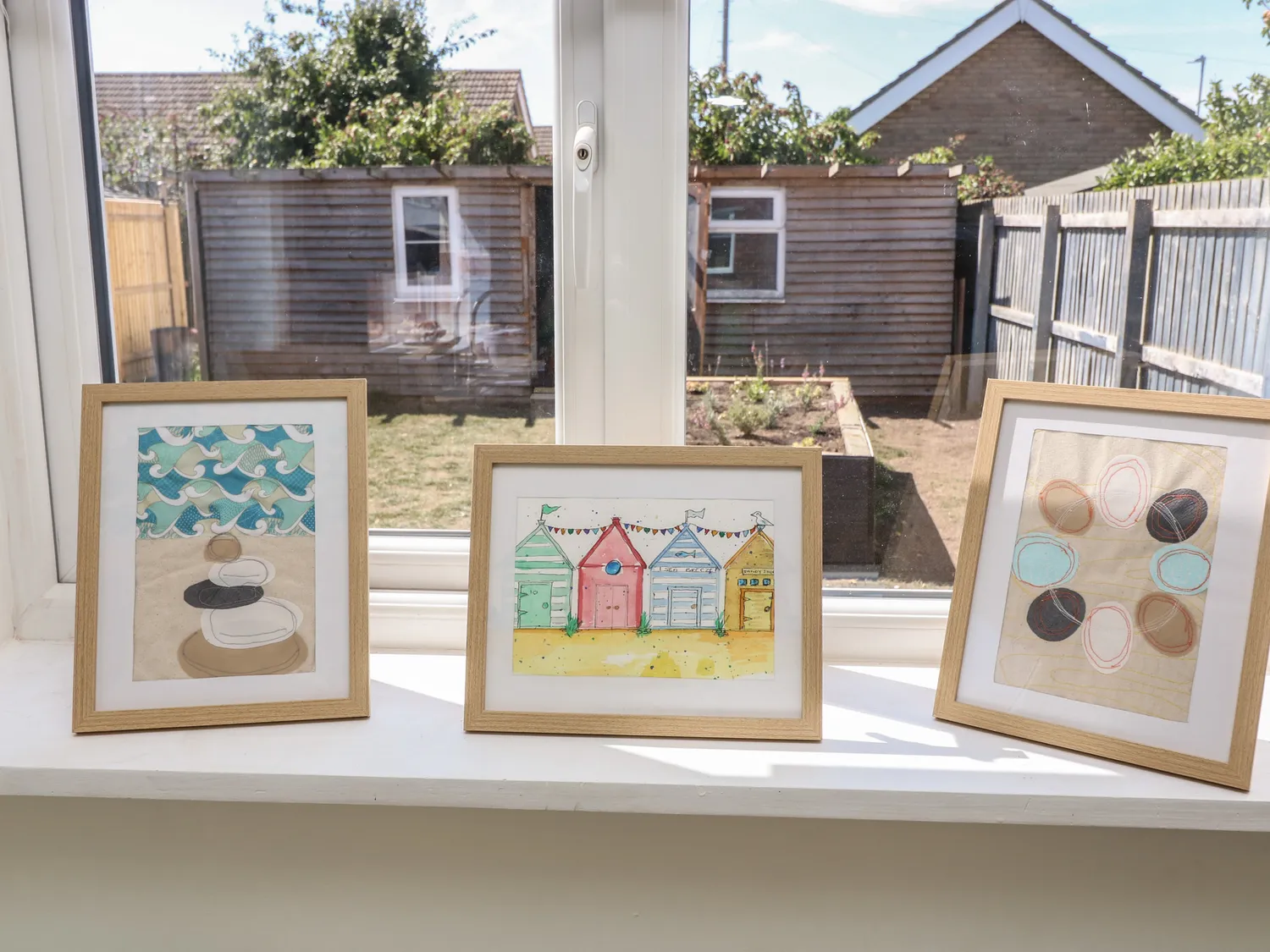 Framed coastal watercolour prints on a sunlit windowsill