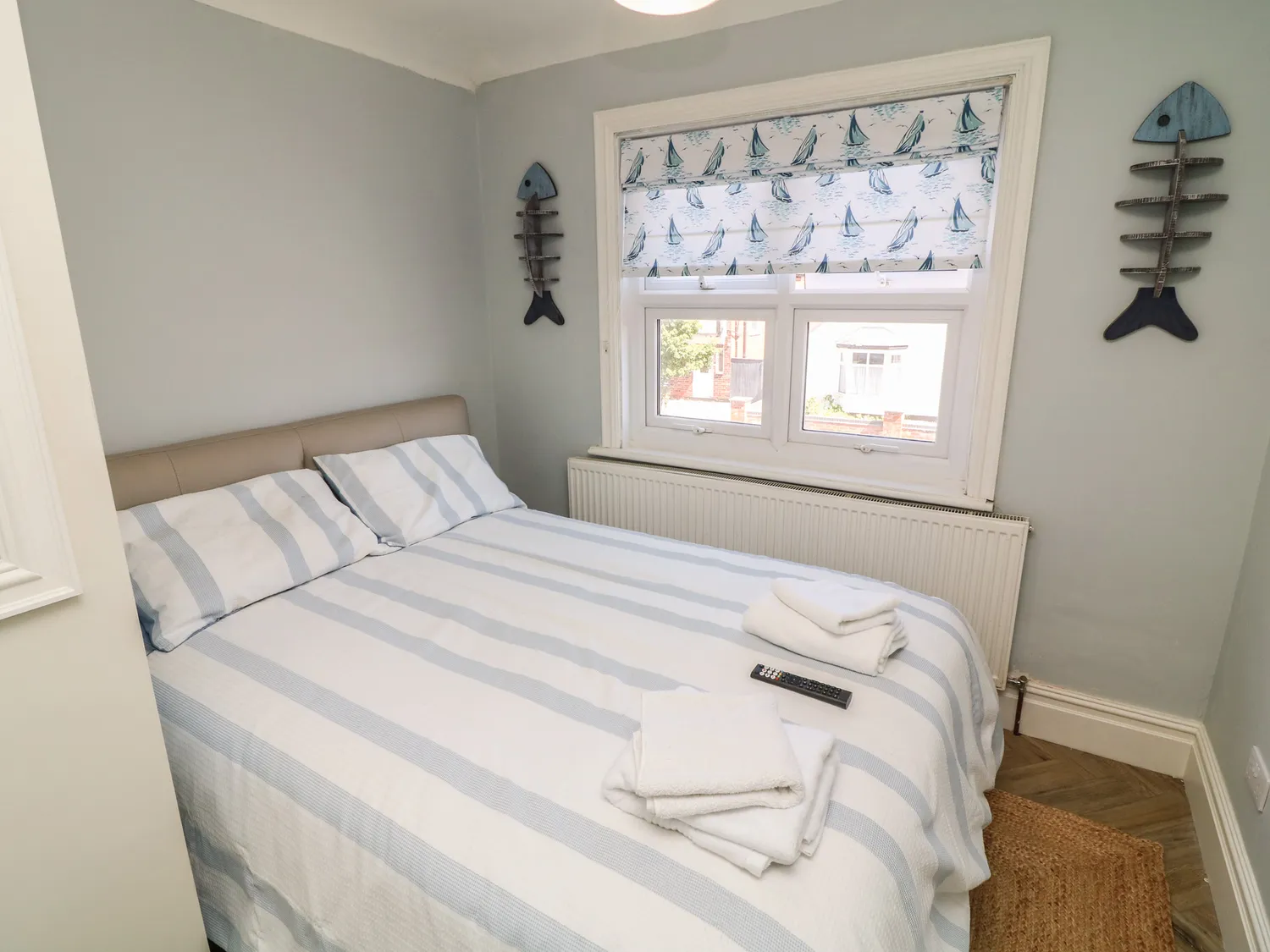 Double bedroom with blue striped bedding and sailboat blind