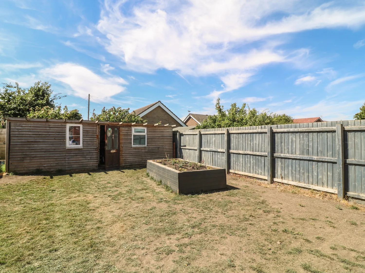 Enclosed rear garden with summerhouse and raised planter
