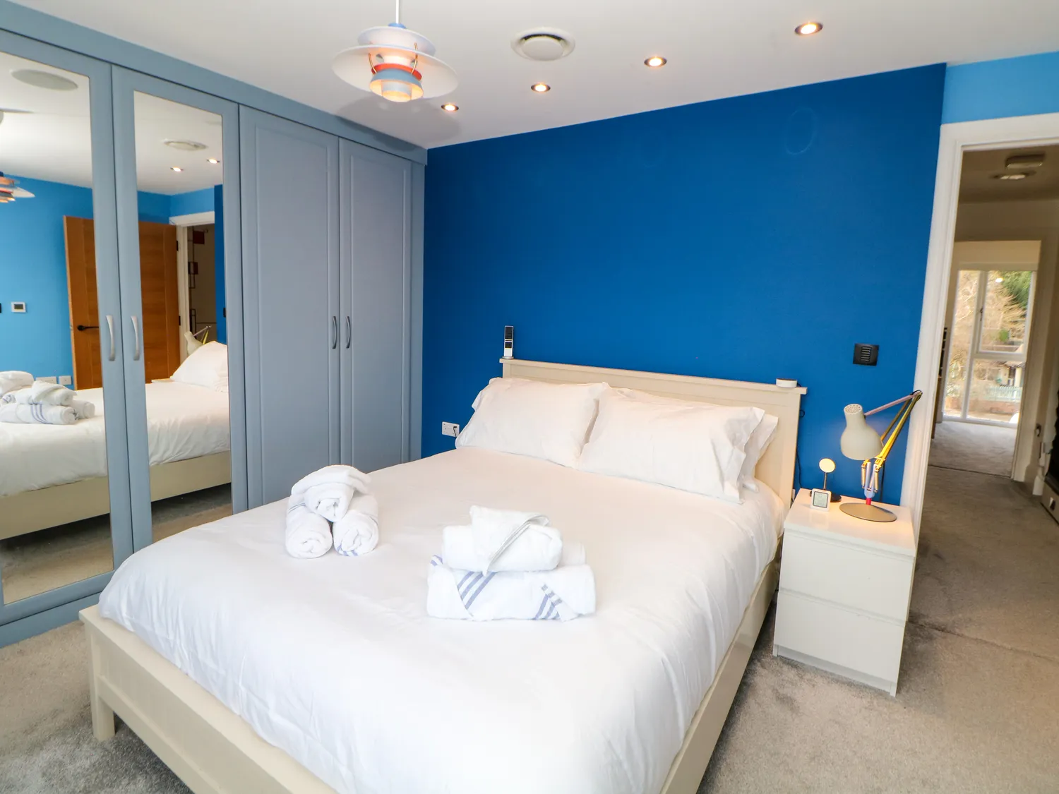 Double bedroom with bold blue feature wall and en-suite access